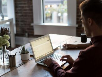 un homme utilisant un ordinateur portable sur une table pour publier des articles invités.