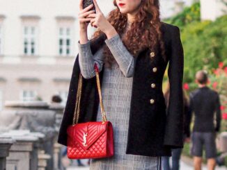femme à la mode en manteau noir tenant un sac à main en cuir rouge