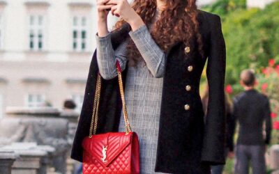 femme à la mode en manteau noir tenant un sac à main en cuir rouge