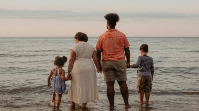 Les Chemins de l'Épanouissement : Naviguer les Défis et les Joies de la Famille Moderne Une famille moderne profite des joies de la plage et du coucher de soleil